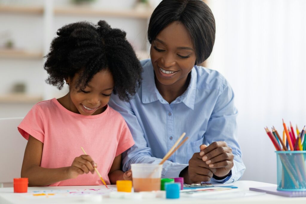 Creative african american little girl painting at daycare